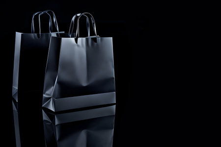 Multiple black shopping and gift bags isolated on dark backgroundの素材