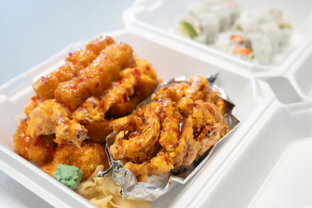 Torched shrimp sushi roll with spicy mayo and teriyaki sauce in take away containerの写真素材