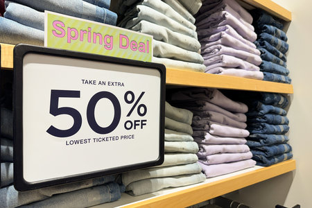 White 50 percent discount sale word banner at clothing store entrance. Seasonal discount offer in...