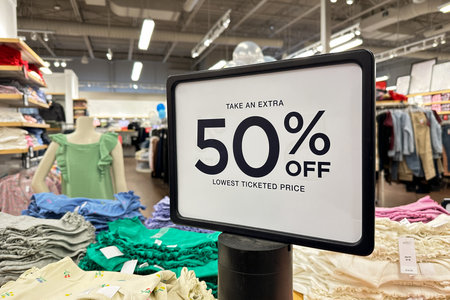 White 50 percent discount sale word banner at clothing store entrance. Seasonal discount offer in...