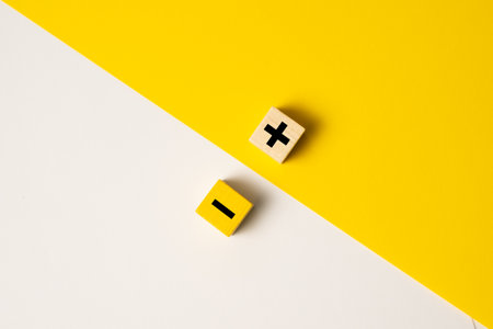 Wood blocks with plus and minus sign on yellow and white background, the concept of opposite, pros...