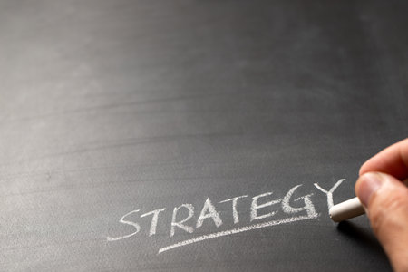 Close-up of a hand writing Strategy on blackboard with white chalk indicating business or marketing planning, with copy space for textの写真素材