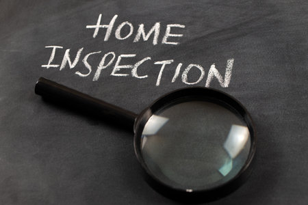 Home inspection words written on a blackboard with white chalk and a magnifying glass.の写真素材