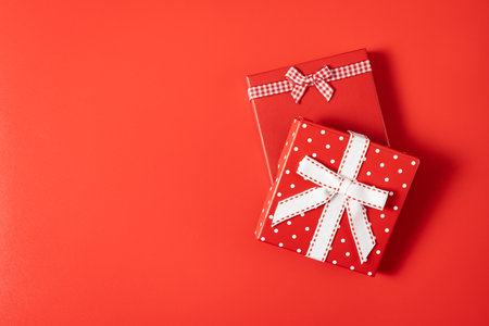 Top view two gift boxes with bow on red background with copy space, can be used for Christmas, wedding, valentine design backgroundの写真素材