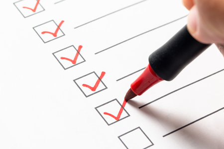 Checklist box with a hand using a red marker pen to check off itemsの写真素材
