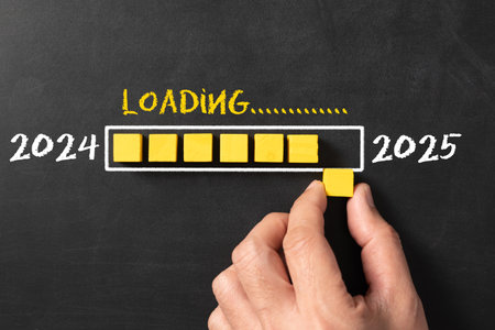 Hand putting wooden cube in progress bar for countdown to 2025, loading year from 2024 to 2025 for new year start conceptの写真素材