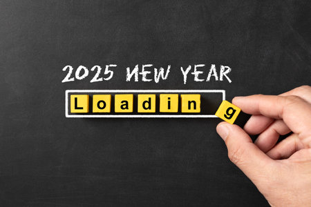 Happy new year 2025 with the word loading spelled out in yellow blocks, symbolizing the upcoming year. A hand is placing the final block as the new year counting downの写真素材