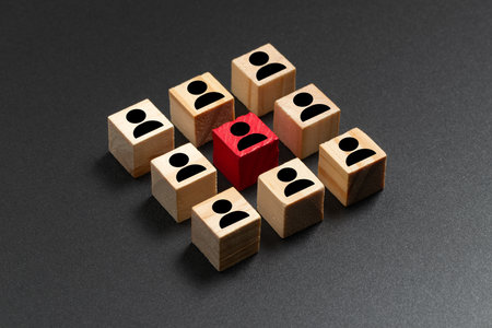 Individuality, showing a red cube with a person icon among wooden cubes with similar icons on a dark background for standing out from the crowd, talent, leadership, outstanding conceptの写真素材