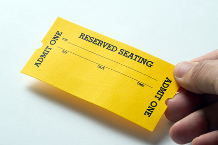 Hand hold a single yellow vintage admission ticket stub isolated on white backgroundの写真素材