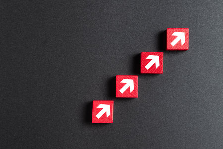 A stack of red wooden blocks with arrows pointing upwards for business, sales, revenue or investment growth conceptの写真素材