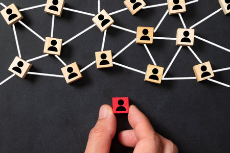 Wooden block cubes connected together with a red cube icon on a black background. Leadership,...