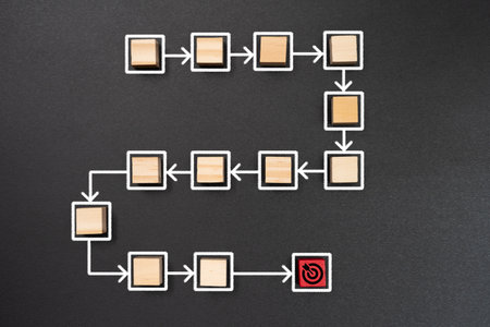 A conceptual process flow diagram with wooden blocks representing steps, white arrows connecting them, and a red target symbol marking the endpoint.の写真素材