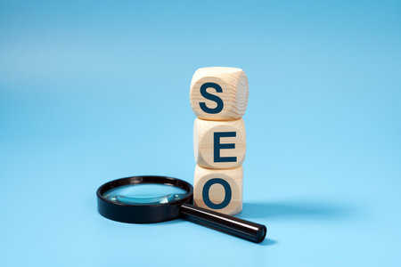 SEO, Search Engine Optimization text wooden cube blocks with a magnifying glass on blue background, idea of strategy, advertising, marketing, keyword and content conceptの写真素材