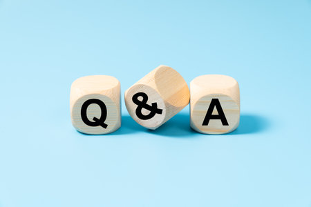 Questions and answers concept with three wooden blocks on light blue background with letters Q and Aの写真素材