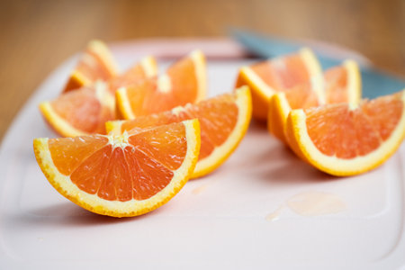 Orange wedges or slices on pink plastic cutting board with a knifeの写真素材