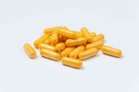 Yellow herbal turmeric medicine capsules or pills isolated on backgroundの写真素材