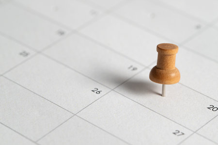 One wooden push pin marking important date on a calendar, symbolizing planning, scheduling, reminders, and organization.の写真素材