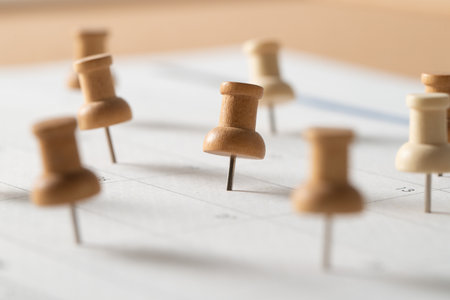 Wooden push pins marking important dates on a calendar, symbolizing planning, scheduling, reminders,...