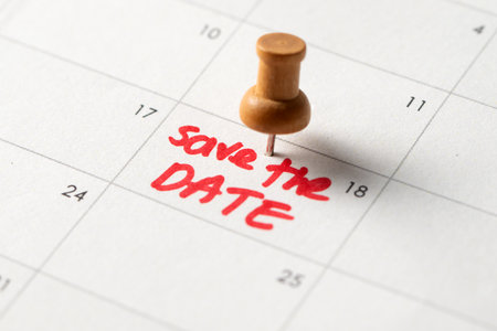 A wooden push pin marks a calendar with Save the Date written in red, symbolizing an important event, reminder, or celebrationの写真素材