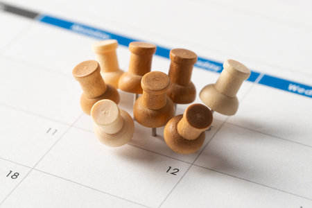 Wooden push pins grouped on a single date of a calendar, symbolizing super important event, appointment, busy schedules, or overlapping tasksの写真素材