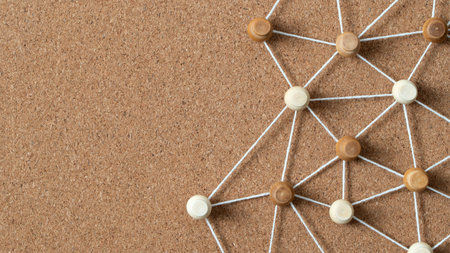 Wooden pushpins connected by white string on a corkboard, illustrating a social network, people connection, or concept map.の写真素材