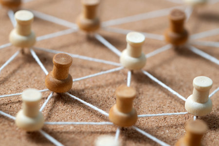 Wooden pushpins connected by white string on a corkboard, illustrating a social network, people connection, or concept map.の写真素材