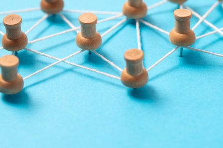 Wooden pushpins or thumbtacks connected by white string on a blue background, illustrating a social...