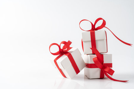 Three square white gift boxes tied with a red satin ribbon for Christmas, New Year, valentines or...