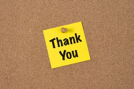 A yellow sticky note with the words Thank You in bold black text pinned to a corkboard. The note conveys gratitude and appreciation in a simple, clear, and cheerful way.の写真素材