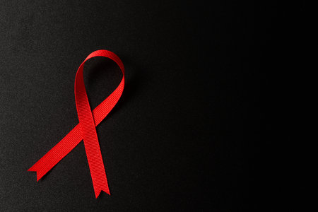 Closeup red ribbon symbolize HIV, world AIDS day awareness ribbon on black background, healthcare and medicine concept.の写真素材