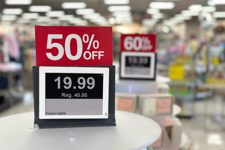 A price tag in a retail store displays a sale promotion price, marked 50 percent discount off the...