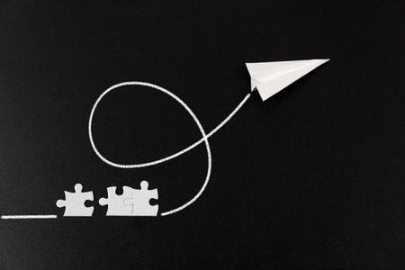 Creative concept of a paper plane launching from puzzle pieces on a dark background, symbolizing problem solving, progress, innovation, and turning ideas into action.