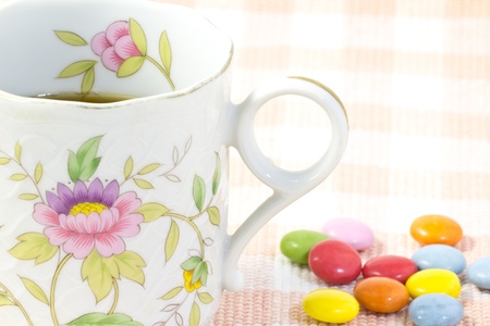 This is a picture of colorful chocolate and coffee cup placed on the table cloth.の写真素材