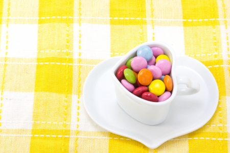 This is a picture of colorful chocolate and coffee cup placed on the table cloth の写真素材
