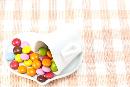 This is a picture of colorful chocolate and coffee cup placed on the table cloth.の写真素材