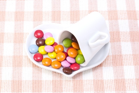 This is a picture of colorful chocolate and coffee cup placed on the table cloth.の写真素材
