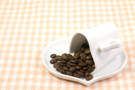 This is a picture of coffee beans and coffee cup on the table cloth.の写真素材