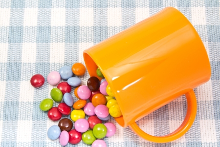 This is a picture of colorful chocolate and mug placed on the table.の写真素材