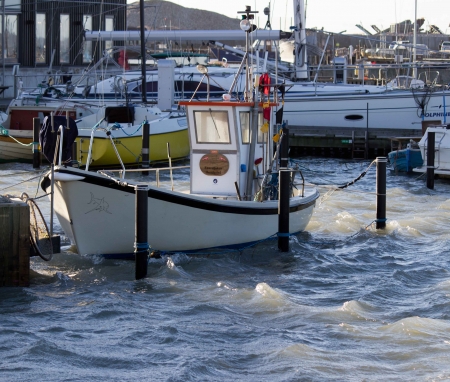 The water level is high in the harbor after the storm and the waves get the boat to cribsのeditorial素材