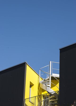 Modern yellow and black building with staircase against blue skyの写真素材