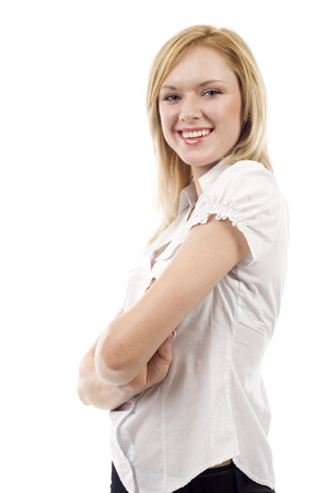 Beautiful young businesswoman standing with hands folded against white backgroundの写真素材