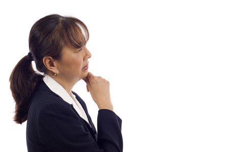 Asian American senior businesswoman showing pensive expression with hand on chin isolated over white backgroundの写真素材