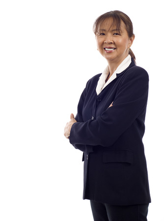 Asian American senior businesswoman standing with hands folded against white backgroundの写真素材