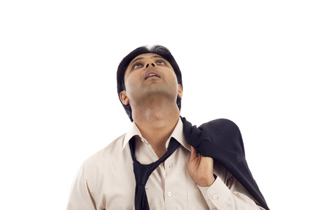 Tired thougful young Indian businessman looking up at copyspace isolated over white backgroundの写真素材