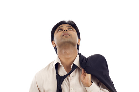 Thoughtful Indian businessman looking up at copyspace isolated over white backgroundの写真素材