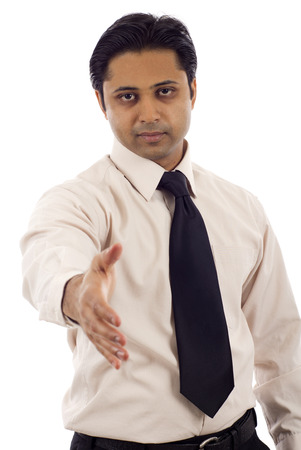 Serious looking Indian businessman offering a handshake isolated over white backgroundの写真素材