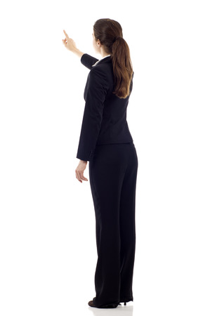 Full body of young business woman pointing at something from the back, isolated over white backgroundの写真素材