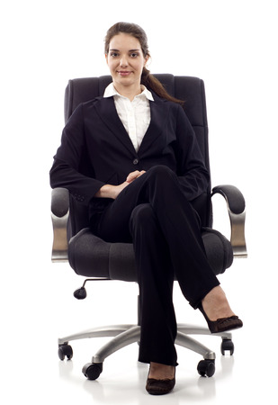 Young confident business woman sitting on a chair isolated on whiteの写真素材