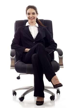 Young happy business woman sitting on a chair isolated on whiteの写真素材