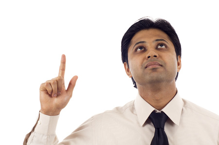 Indian Businessman looking up, pointing at copyspace isolated over white backgroundの写真素材
